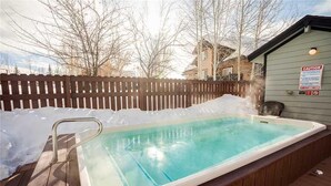 A hot tub with a wooden deck and a wooden fence in the background. - Quail Run - 3367 (Steamboat Springs)