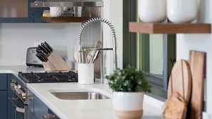A modern kitchen with a central island, built-in appliances, and wooden shelves.