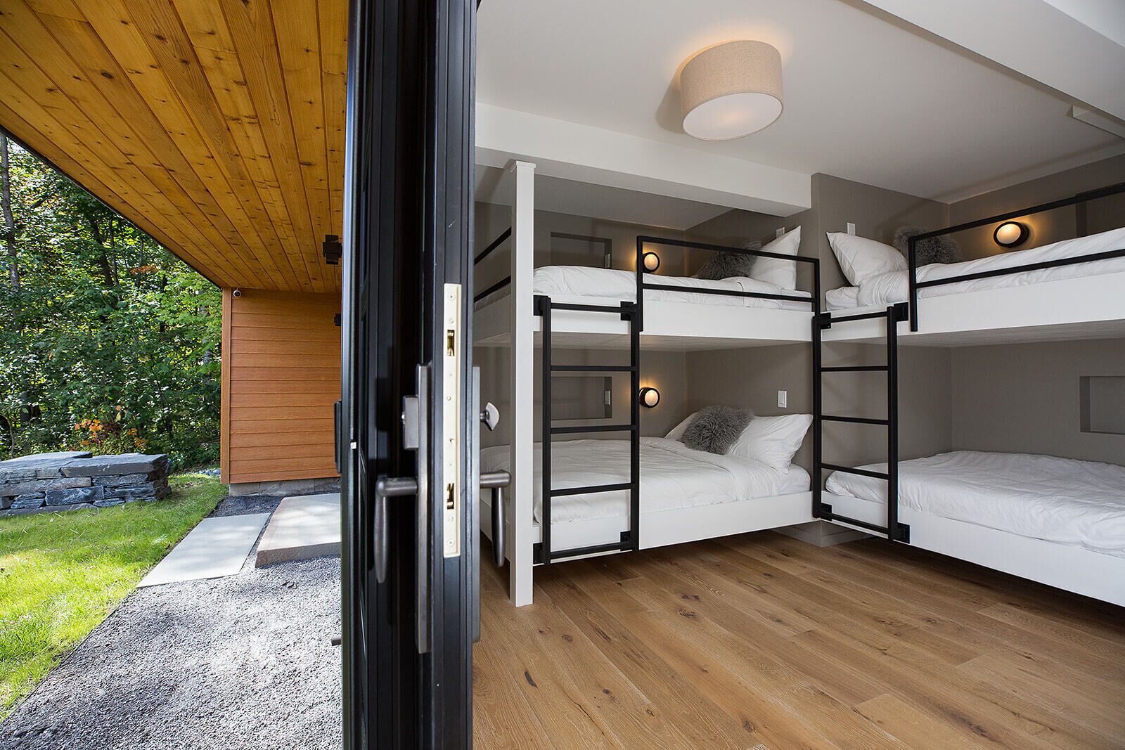 Een modern interieur met stapelbedden, een houten plafond en een stenen muur buiten.
