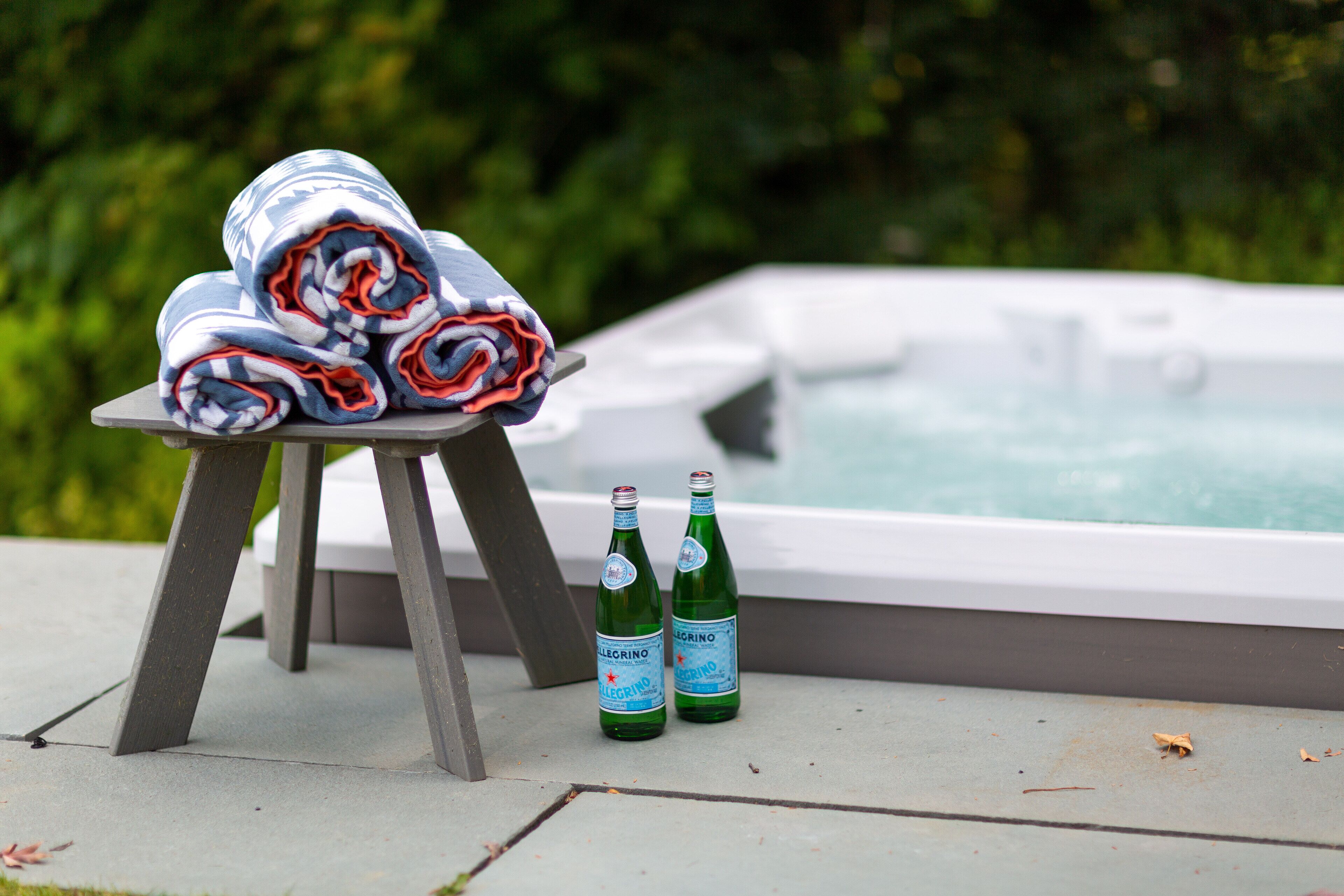 Ein Whirlpool mit zwei Bierflaschen und zusammenrollten Handtüchern auf einem Tisch.