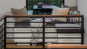 A modern room with a large window offering a scenic view, a built-in bench with books, and pendant lighting.