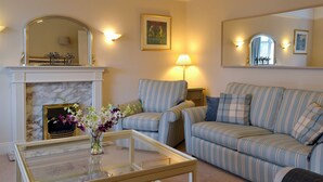 A living room with a fireplace, striped sofas, a glass coffee table, and wall-mounted lamps. - 3 bedroom accommodation in Keswick (Keswick)