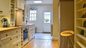 A kitchen with wooden cabinets, a countertop, and a stool. - 3 bedroom accommodation in Keswick (Keswick)