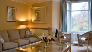 A living room with a sofa, chairs, a glass coffee table, and a view of a tree through a window. - 3 bedroom accommodation in Keswick (Keswick)
