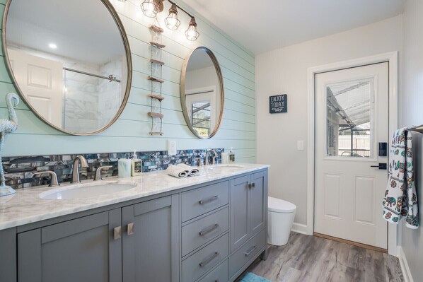 Une salle de bain avec deux lavabos, un grand miroir et un porte-serviettes.