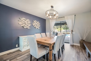 Relax in this inviting dining area with a table for six, a stunning view of the pool, and a unique fish-themed wall art.