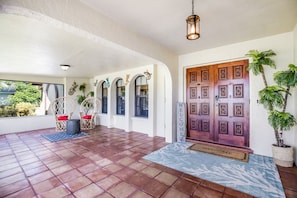 Enter a beautifully appointed space with a wooden door, potted plants, and a cozy wicker chair.