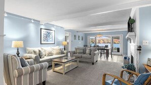 A spacious living room with a sofa, armchairs, and a coffee table. There is a dining area with a table and chairs, and a view of the outdoors. - Pet friendly, waterfront, home on Lake Leelanau. Pontoon available for rent (Lake Leelanau)