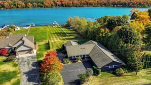 A residential area with houses, a well-maintained lawn, and a lake. - Pet friendly, waterfront, home on Lake Leelanau. Pontoon available for rent (Lake Leelanau)