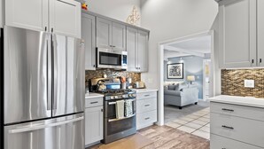 A modern kitchen with stainless steel appliances, white cabinetry, and a tiled backsplash. - Pet friendly, waterfront, home on Lake Leelanau. Pontoon available for rent (Lake Leelanau)