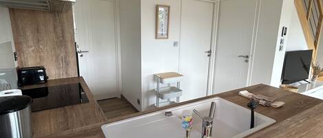 A modern kitchen with a wooden countertop, a sink, and a coffee machine.