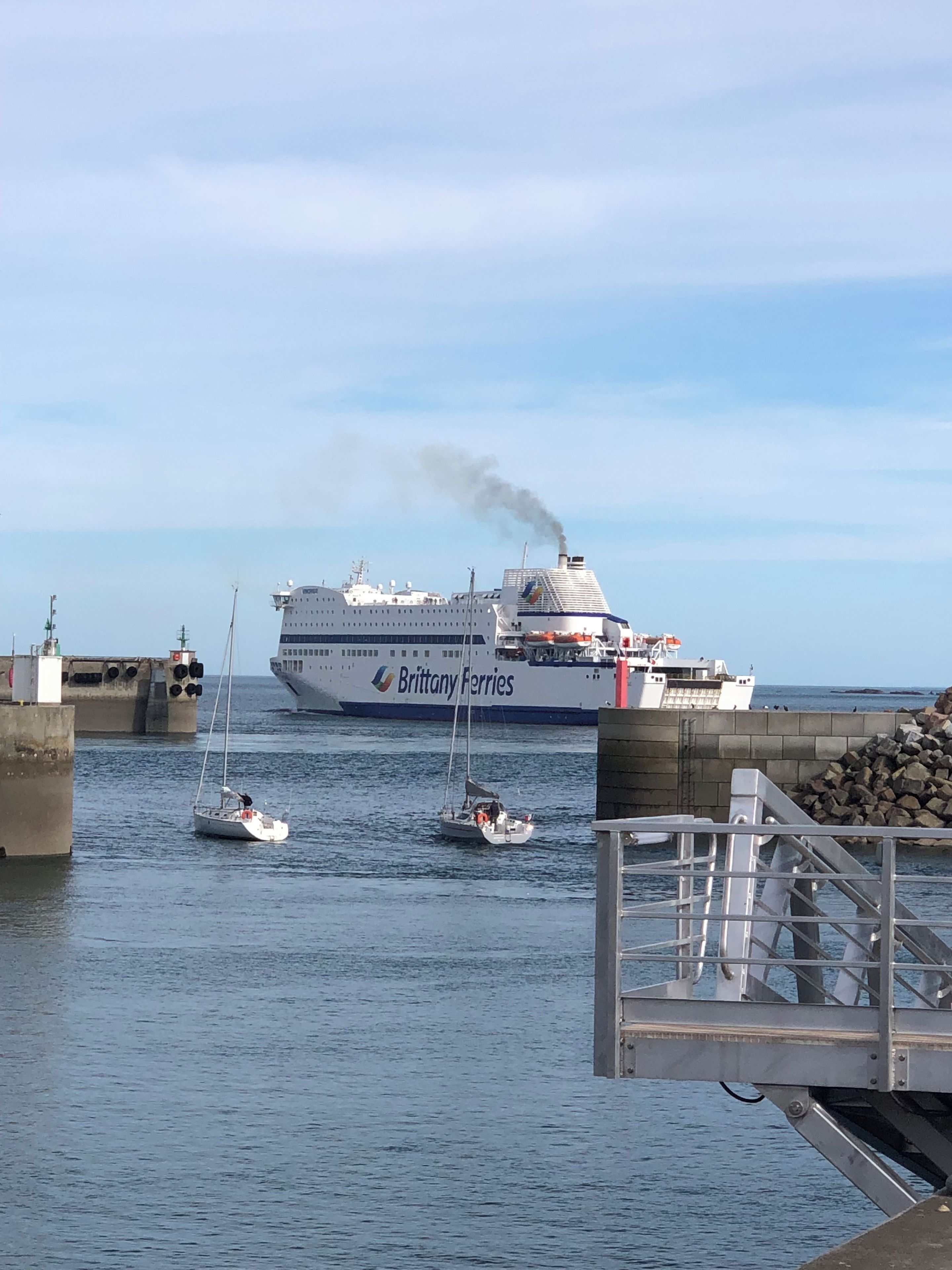 Un gran barco crucero llamado 'Brittany Ferries' atracado en un puerto, con embarcaciones más pequeñas cerca.