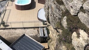 Een hottub met uitzicht op zee, een rotsachtige richel en een zonnepaneel.
