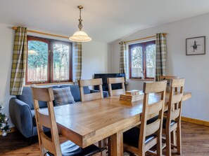 A dining area with a wooden table and chairs, a sofa, and plaid curtains on windows. - 4 bedroom accommodation in Cayton, near Scarborough (Cayton, near Scarborough)