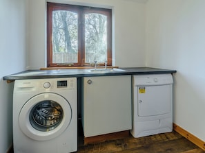 Une cuisine compacte équipée d’un lave-linge, d’un petit réfrigérateur et d’un évier.