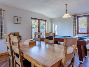 A wooden dining table with chairs, a pool table, and a ceiling light fixture. - 4 bedroom accommodation in Cayton, near Scarborough (Cayton, near Scarborough)