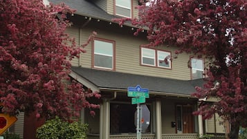 Traditional two-story house with a gabled roof and porch, featuring a railing and entryway.