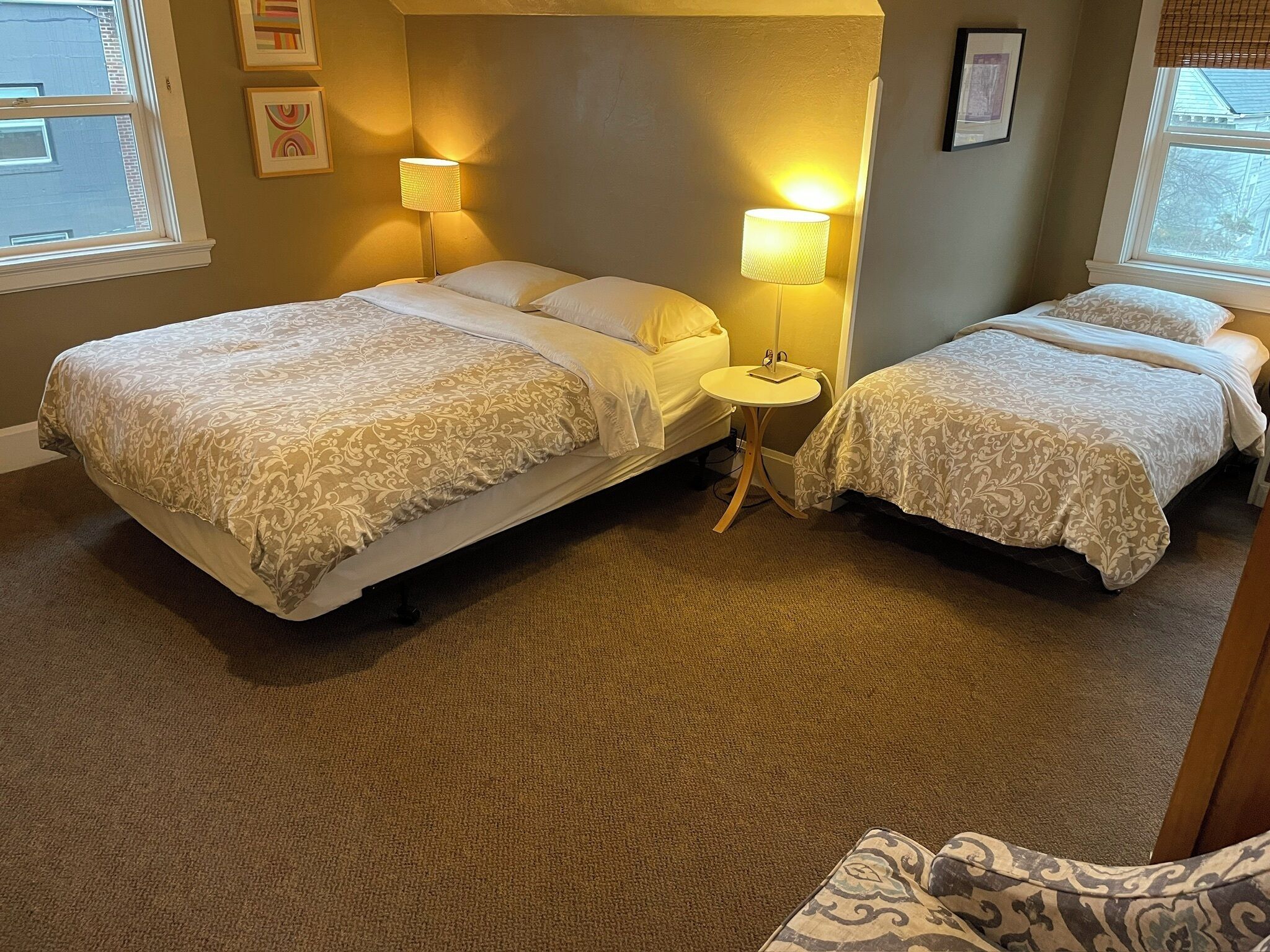 Une chambre d’hôtel avec deux lits, une petite table ronde et deux lampes.