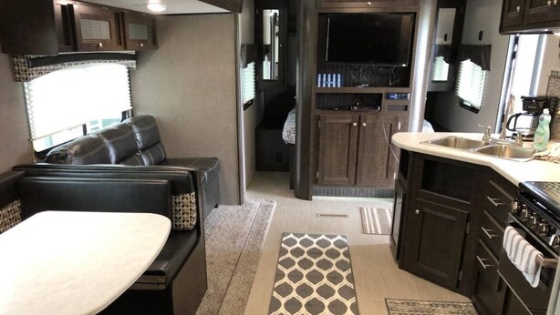 Un intérieur de camping-car compact comprenant un coin repas, une kitchenette et une salle de bain.