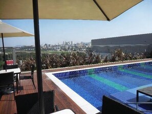 A rooftop pool with a city view, surrounded by outdoor seating and a large umbrella. - 123 Expo Anhembi (São Paulo)
