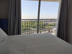 A hotel room with a large bed, a view of a cityscape through a balcony with a metal railing. - 123 Expo Anhembi (São Paulo)