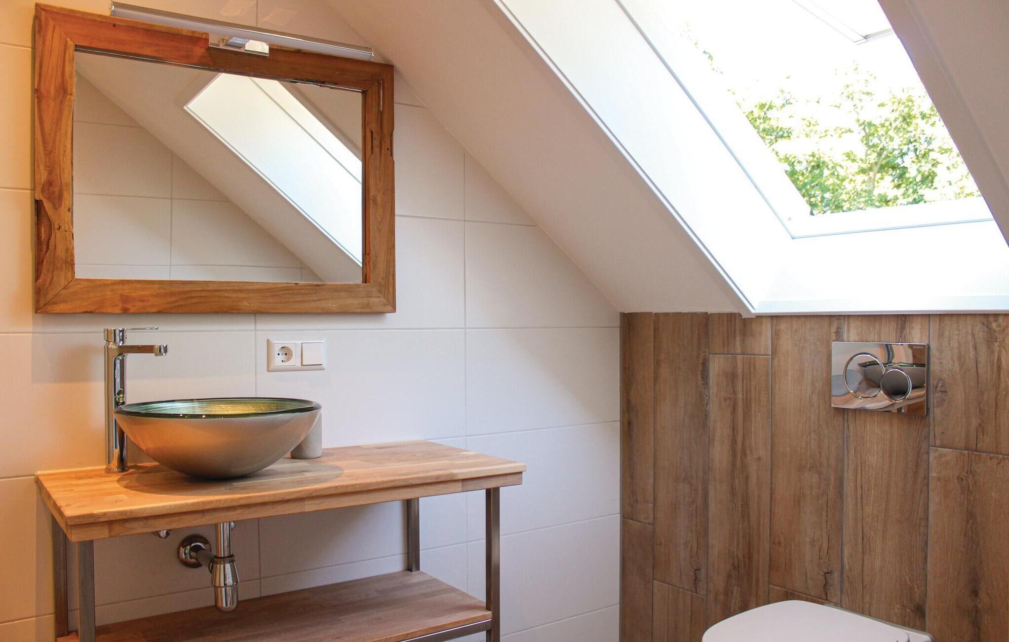 Ein modernes Badezimmer mit Oberlicht, einem Holzkosmetikschrank und einem großen Spiegel.