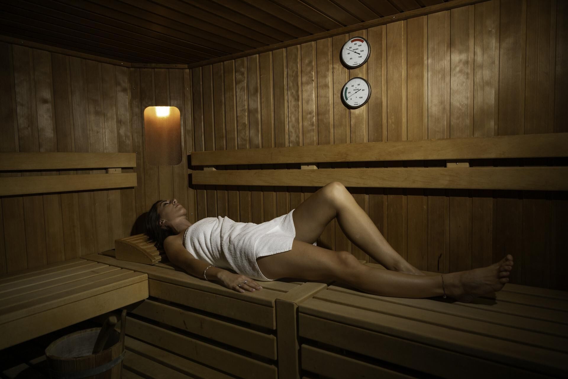 A sauna with wooden benches and two visible temperature gauges.