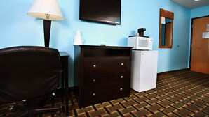 Une chambre d’hôtel équipée d’une télévision, d’un four à micro-ondes, d’une commode et d’une chaise.
