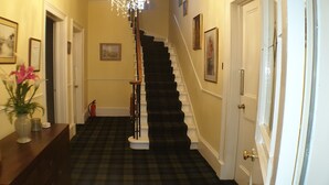A hallway with a black and white checkered floor, a staircase, and framed pictures on the walls. - Creag Dhubh Country House (Inveraray)