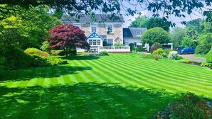 A well-manicured lawn with a stone house in the background. - Creag Dhubh Country House (Inveraray)