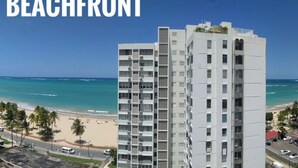 A high-rise hotel with a beachfront view, featuring multiple balconies and a modern architectural design.