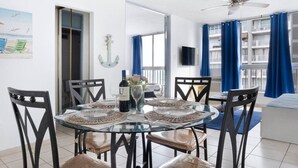 A dining area with a round glass table, black chairs, and a bottle of wine.