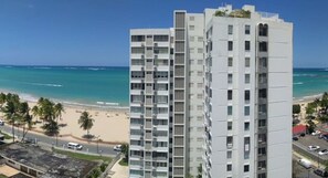 A high-rise hotel with a beachfront view, featuring multiple balconies and a modern architectural design.