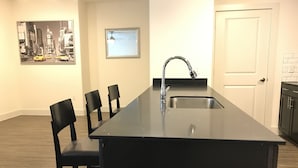 Una cocina moderna con encimera negra, pileta de acero inoxidable y cuatro sillas negras.