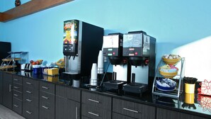 Un angolo caffè self-service con diverse macchine da caffè e una selezione di bicchieri usa e getta.
