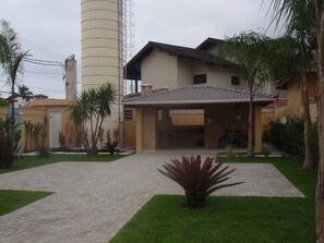 A residential building with a tiled roof, a garage, and a paved driveway. - Spacious and comfortable house in a gated community, private pool, beach service. (São Sebastião)