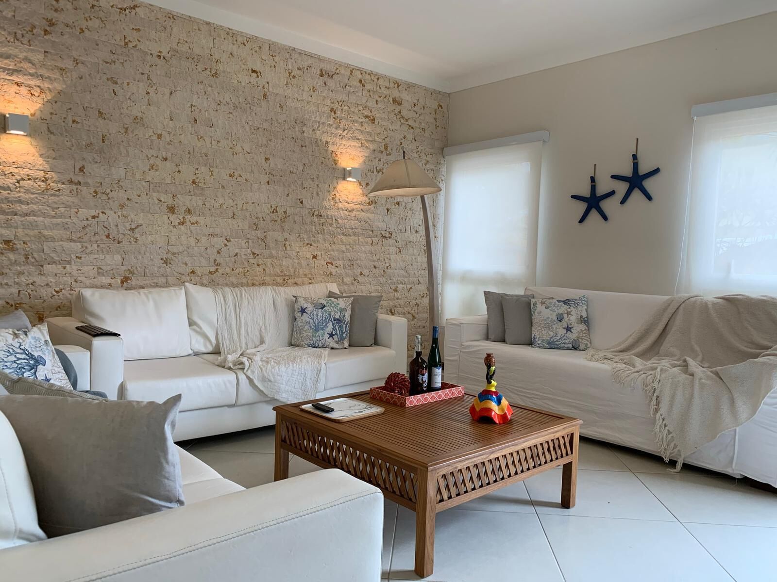 A living room with two white sofas, a wooden coffee table, and a brick-patterned wall.