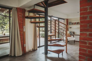 A modern interior with a wooden spiral staircase, a brick wall, and a bookshelf.