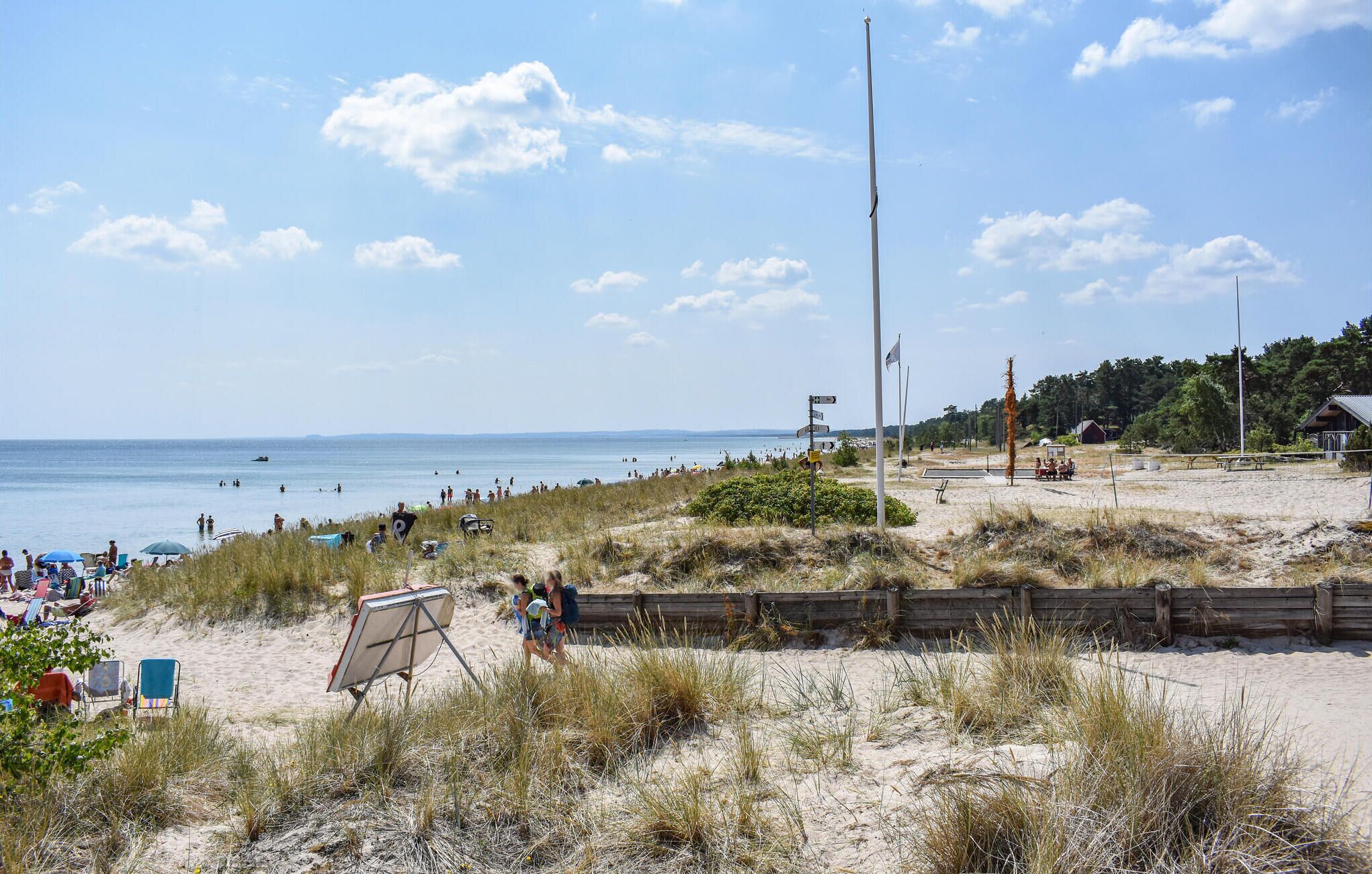 En strand med sandet forgrund, et træhegn og frit udsyn til havet.