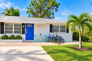 A single-story house with a blue front door, numbered 699, and a small porch with two chairs and a table. - Sea Breeze Hideaway- Near Beach and Mercato for dining,shops-Fenced doggie area (Naples)