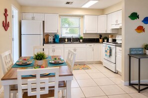 A modern kitchen with white cabinets, a dining table with chairs, and a kitchen island.