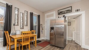 A compact kitchen with a stainless steel refrigerator, wooden dining table, and chairs. - Pet and kid friendly duplex with 2 bedrooms (Pacific)