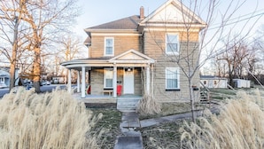 A two-story house with a front porch, a chimney, and a small front yard with tall grasses. - Pet and kid friendly duplex with 2 bedrooms (Pacific)