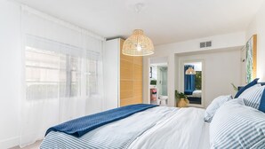 Een moderne slaapkamer met een groot bed, een hanglamp en uitzicht op de badkamer.