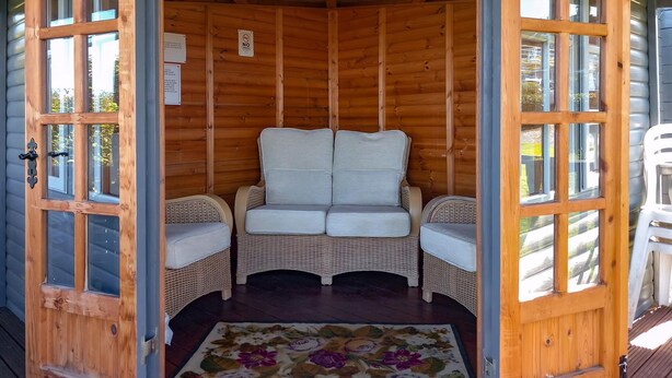 Ein gemütliches Holzhaus mit einer zentralen Sitzecke, ausgestattet mit zwei gepolsterten Sesseln und einem Sofa.