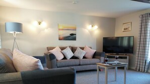 Ein Wohnzimmer mit einer Couch, einem Couchtisch, einem Fernseher und einer Lampe.