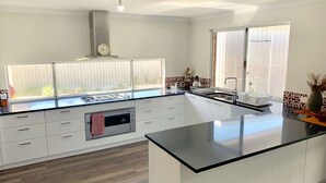A modern kitchen with a central island, double sink, and a built-in oven. - Tranquil Waters -  located 100m from the shores of Geographe Bay (WEST BUSSELTON)