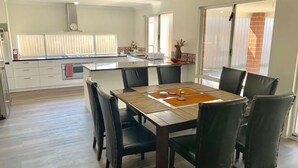 A modern kitchen with a central island, dining table with chairs, and large windows. - Tranquil Waters -  located 100m from the shores of Geographe Bay (WEST BUSSELTON)