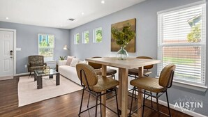 Una sala de estar moderna con comedor, que incluye una mesa de madera, sillas de mimbre, un sofá y una mesa baja.