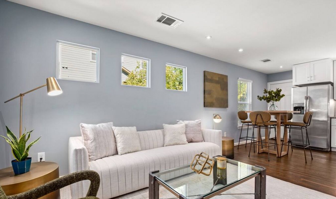A modern living room with a sofa, coffee table, and a dining area with chairs.